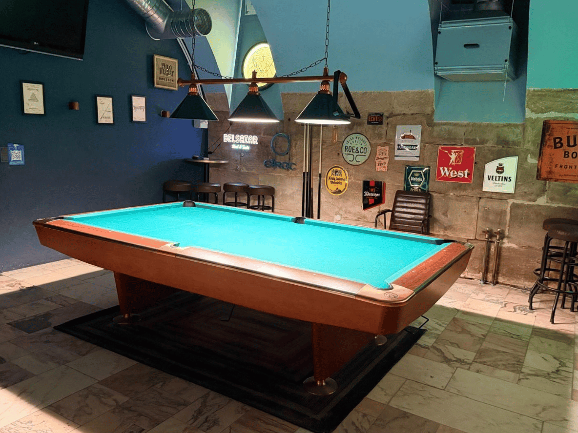 Pooltisch im Billardraum von Pub&Go Fürth mit drei Hängelampen vor der Sandsteinwand